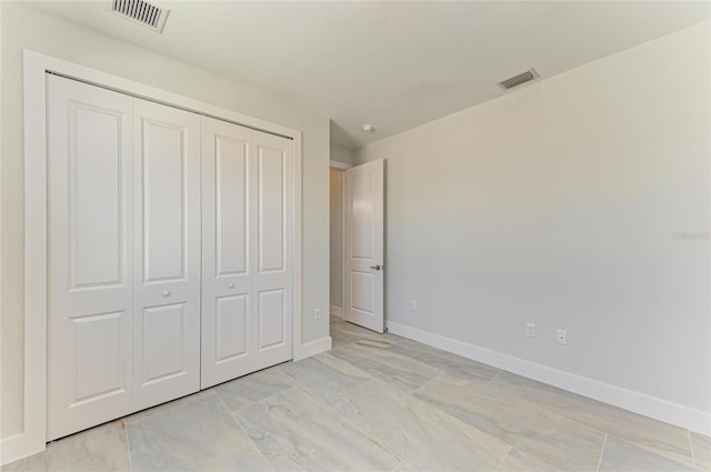 unfurnished bedroom with a closet, visible vents, and baseboards