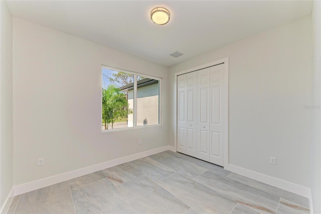 unfurnished bedroom featuring visible vents, a closet, and baseboards