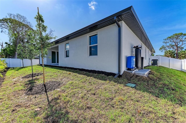 back of house with stucco siding, a yard, and a fenced backyard