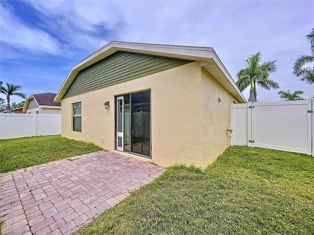 back of house with fence, a patio, stucco siding, and a yard