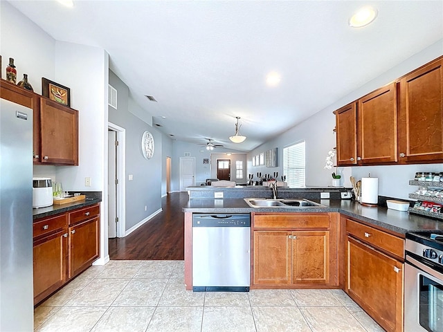 kitchen with a sink, brown cabinetry, stainless steel appliances, open floor plan, and a peninsula