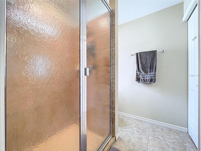 bathroom with baseboards, tile patterned flooring, and a stall shower