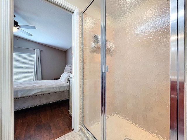 ensuite bathroom with wood finished floors, lofted ceiling, a shower stall, a ceiling fan, and ensuite bath