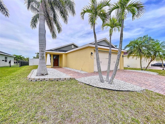 view of front of home with a front lawn, fence, decorative driveway, stucco siding, and an attached garage