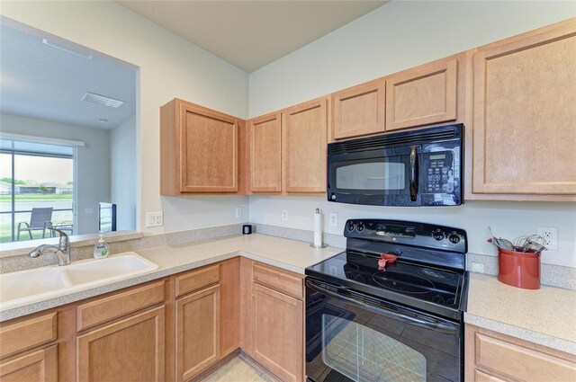 kitchen with black appliances, light brown cabinets, light countertops, and a sink