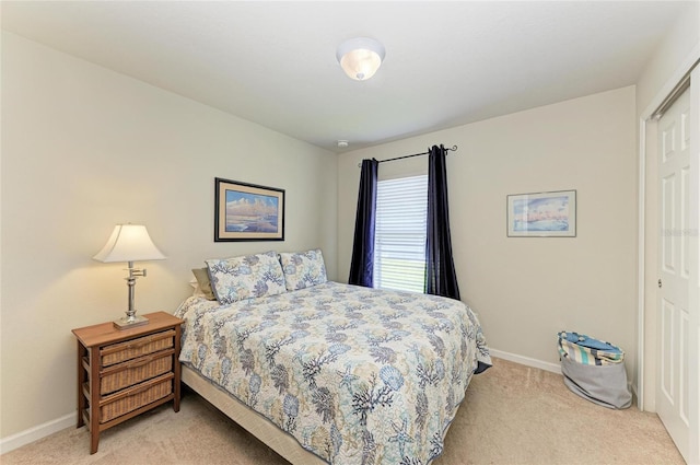 bedroom featuring a closet, light colored carpet, and baseboards