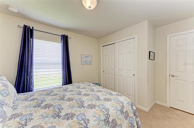 bedroom featuring a closet, baseboards, and light carpet