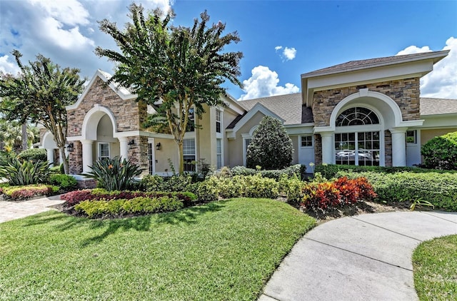 view of front of home featuring a front lawn, stone siding, and stucco siding