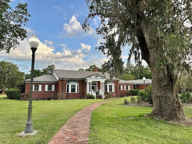 708 E Main St, Wauchula, FL 33873 - neoclassical home featuring a chimney, brick siding, and a front lawn