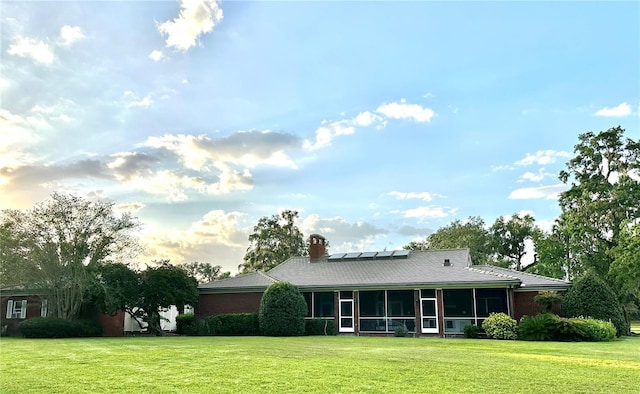 708 E Main St, Wauchula, FL 33873 - rear view of property featuring a yard, a chimney, a sunroom, and solar panels