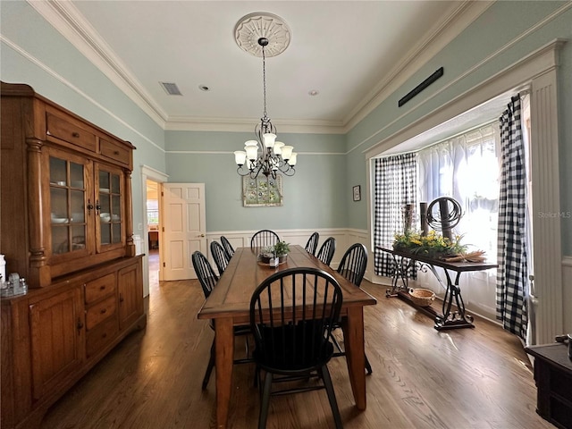 708 E Main St, Wauchula, FL 33873 - dining space featuring a wainscoted wall, dark wood-type flooring, visible vents, an inviting chandelier, and crown molding
