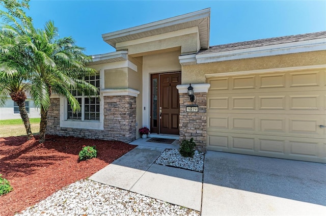 entrance to property with a garage, stucco siding, driveway, and stone siding
