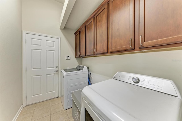 laundry area featuring light tile patterned floors, cabinet space, independent washer and dryer, and baseboards
