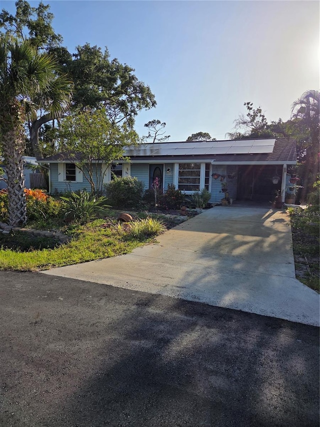 ranch-style home featuring a carport, driveway, and solar panels
