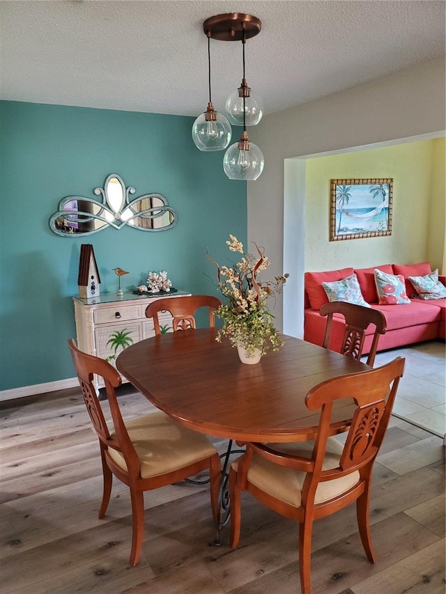 dining area with light wood-style flooring and a textured ceiling