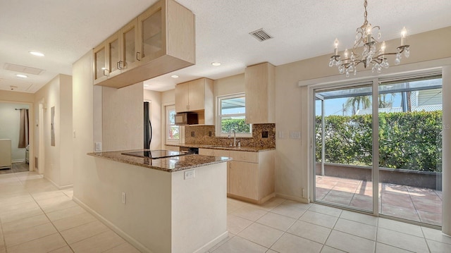 2259 Pueblo Ln Unit V38, Sarasota, FL 34231 - kitchen with light tile patterned floors, dark stone counters, tasteful backsplash, light brown cabinetry, and black electric cooktop