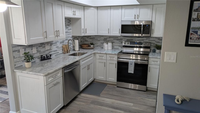 4158 Tamiami Trl Unit V1, Port Charlotte, FL 33952 - kitchen with light stone counters, stainless steel appliances, light wood-style floors, backsplash, and a sink
