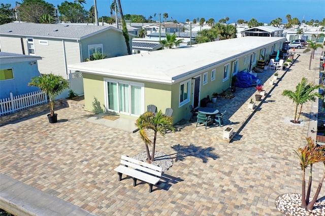 rear view of house featuring fence, stucco siding, a patio area, and a residential view