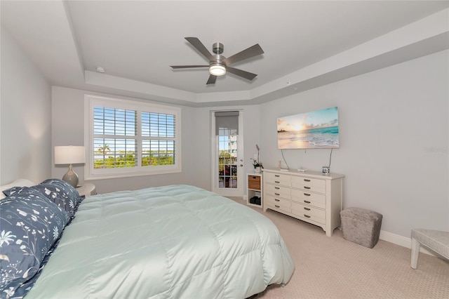 bedroom with baseboards, a ceiling fan, a tray ceiling, and light carpet