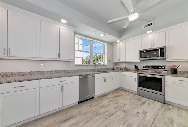 kitchen with visible vents, appliances with stainless steel finishes, light wood-type flooring, a sink, and white cabinets