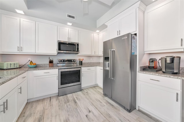 kitchen featuring visible vents, light stone countertops, light wood-style floors, white cabinetry, and stainless steel appliances
