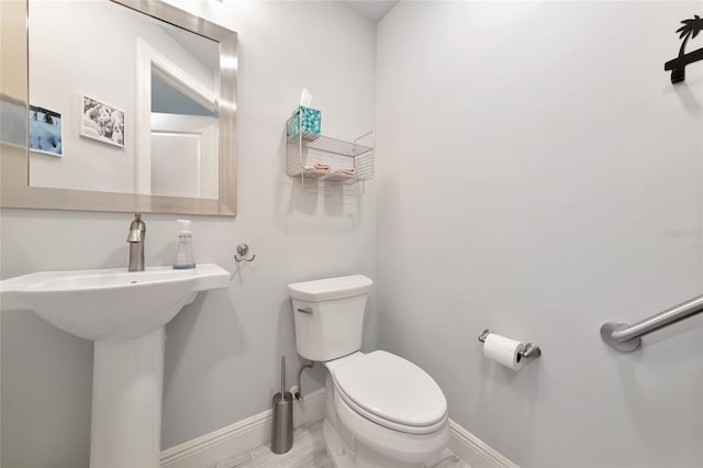 bathroom with a sink, baseboards, and toilet