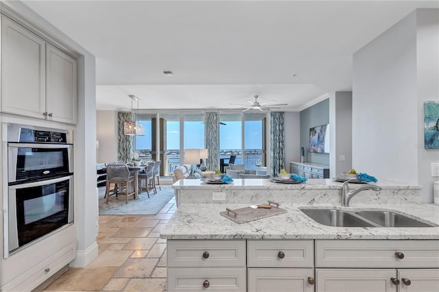 130 Riviera Dunes Way Unit 502, Palmetto, FL 34221 - kitchen featuring light stone countertops, stainless steel double oven, a sink, open floor plan, and stone tile flooring