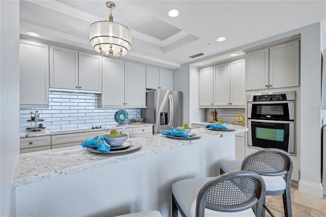 130 Riviera Dunes Way Unit 502, Palmetto, FL 34221 - kitchen featuring appliances with stainless steel finishes, a raised ceiling, recessed lighting, tasteful backsplash, and a kitchen bar