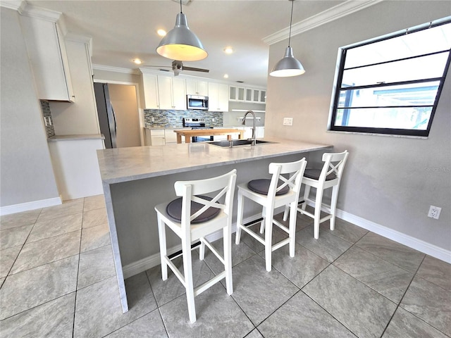 2204 34th St W, Bradenton, FL 34205 - kitchen with appliances with stainless steel finishes, a sink, ornamental molding, backsplash, and a kitchen bar