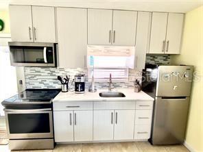 kitchen featuring appliances with stainless steel finishes, tasteful backsplash, light countertops, and a sink