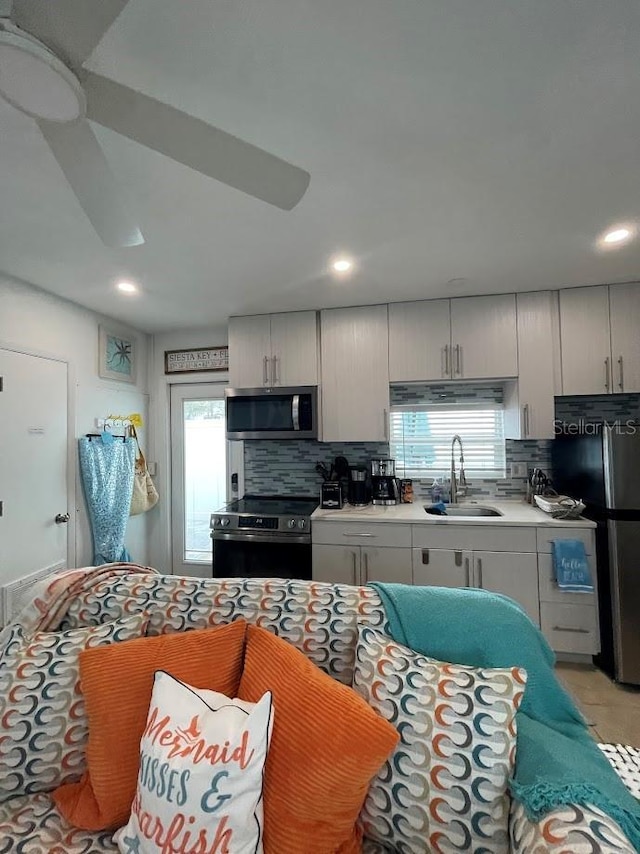 kitchen with a wealth of natural light, appliances with stainless steel finishes, decorative backsplash, and a sink