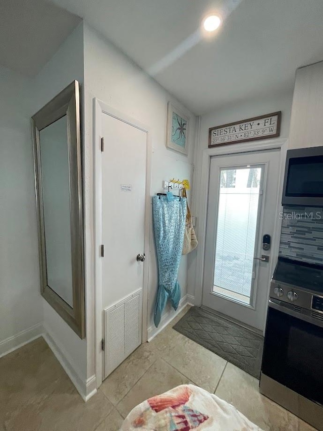 doorway featuring light tile patterned floors, visible vents, and baseboards