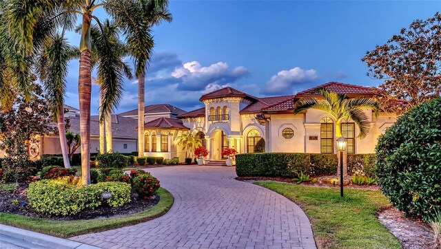 view of front of property with curved driveway, stucco siding, and a tiled roof