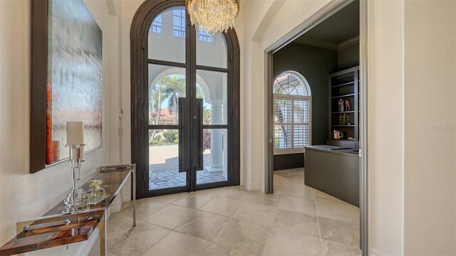 doorway to outside with a textured wall, ornamental molding, french doors, and a chandelier