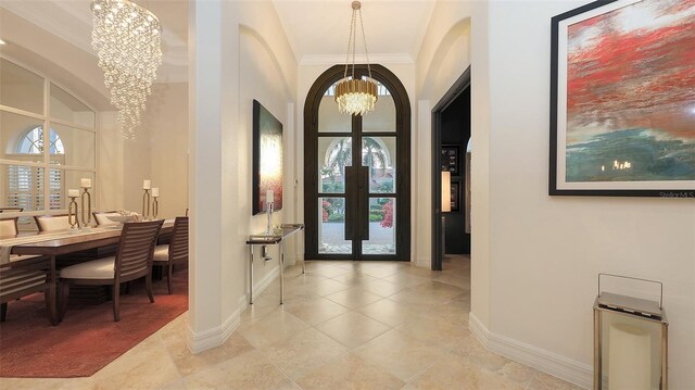 foyer entrance with arched walkways, a chandelier, french doors, baseboards, and ornamental molding