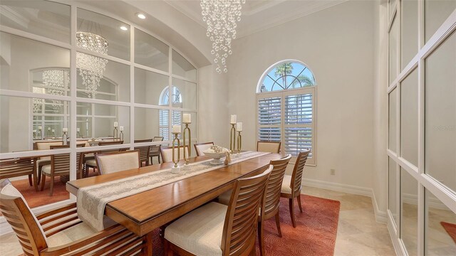 dining area featuring crown molding, an inviting chandelier, baseboards, a high ceiling, and recessed lighting