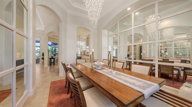 dining space with ornamental molding, light tile patterned flooring, baseboards, a high ceiling, and arched walkways