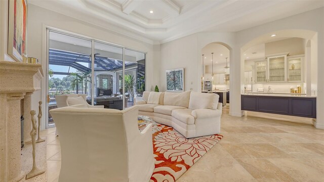 living area featuring arched walkways, beamed ceiling, ornamental molding, coffered ceiling, and recessed lighting