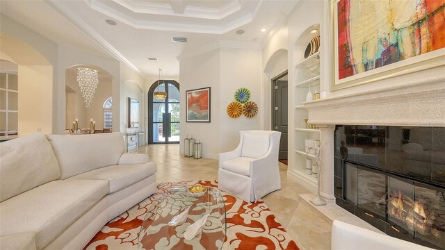 living room with arched walkways, built in shelves, a glass covered fireplace, ornamental molding, and light tile patterned flooring