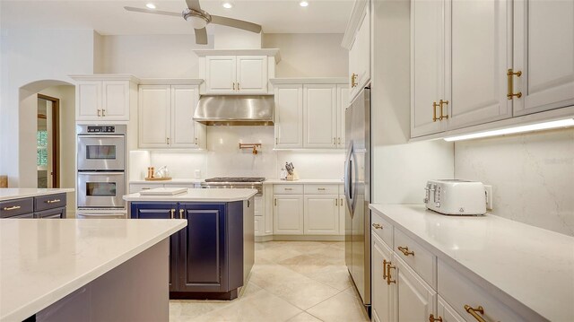 kitchen featuring appliances with stainless steel finishes, arched walkways, a ceiling fan, white cabinetry, and under cabinet range hood