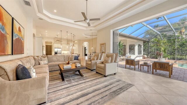 living area featuring visible vents, a ceiling fan, a raised ceiling, arched walkways, and light tile patterned floors