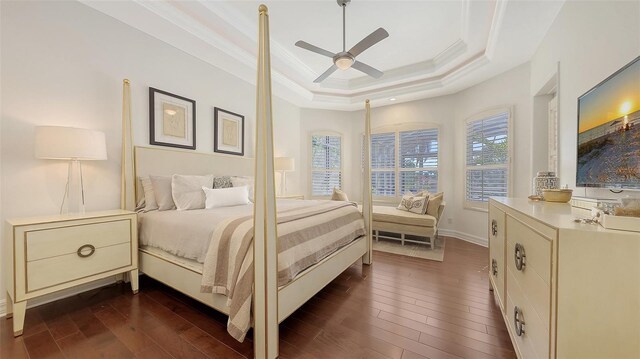 bedroom with dark wood-type flooring, ornamental molding, a raised ceiling, and a ceiling fan