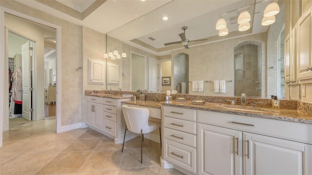 full bathroom with ceiling fan, vanity, baseboards, a spacious closet, and tiled shower