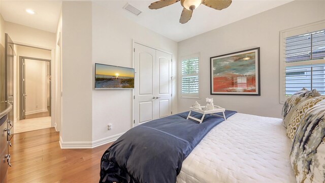 bedroom featuring light wood-style floors, a ceiling fan, baseboards, visible vents, and a closet