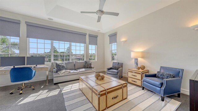 carpeted living area with baseboards and ceiling fan