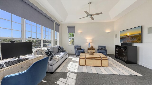 living room with carpet flooring, ceiling fan, baseboards, and a towering ceiling