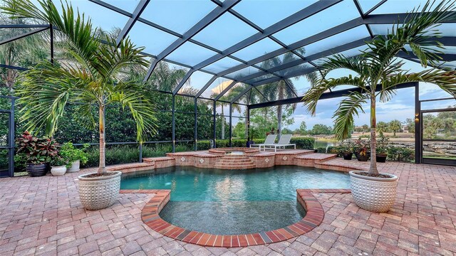 view of pool featuring glass enclosure, a pool with connected hot tub, and a patio