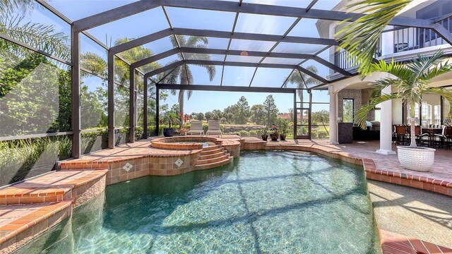 view of pool featuring outdoor dining space, a patio, a pool with connected hot tub, and glass enclosure