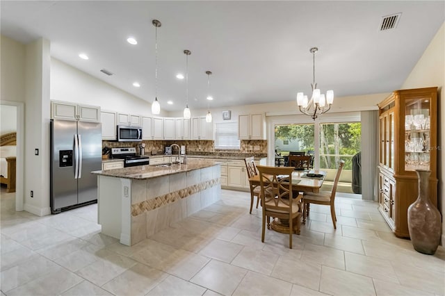 kitchen featuring appliances with stainless steel finishes, lofted ceiling, tasteful backsplash, a sink, and light stone counters