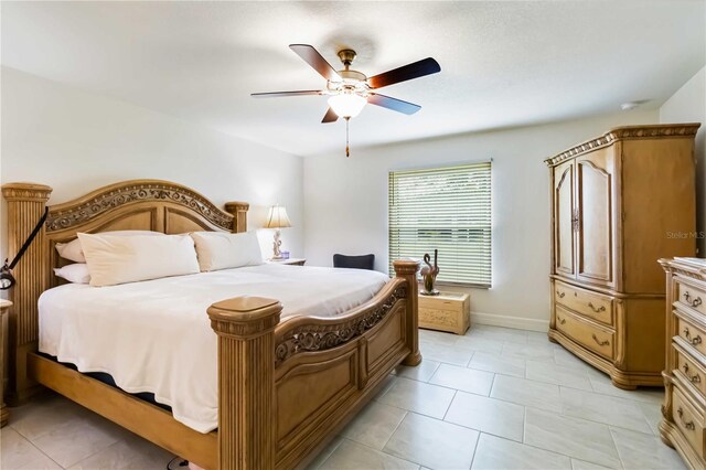 bedroom featuring a ceiling fan, light tile patterned flooring, and baseboards